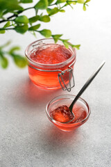red fruity jelly in glass jar and spoon