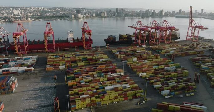 Aerial close-up panning view of a container ships docked at Durban harbour, Durban skyline in the background,South Africa