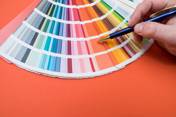 man choosing color in wheel palette isolated on orange