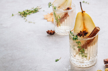 Traditional autumn spicy cocktail with pear. Cold pear white tea or mulled wine with cinnamon, thyme and anise on the light beige background