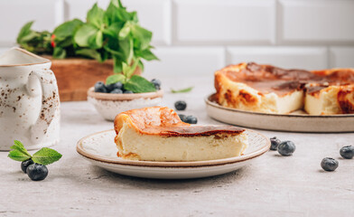 A piece of Basque burnt cheesecake put, the whole cake is at the background. Tarta de Queso.