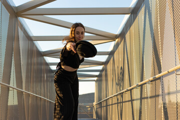young dancer throwing a hat while dancing urban dance on the street at sunset