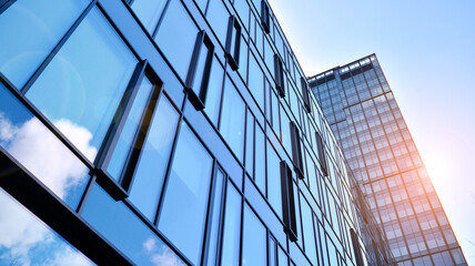 Obraz premium Modern office building with glass facade on a clear sky background. Abstract close up of the glass-clad facade of a modern building covered in reflective plate glass.