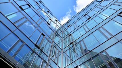 Fototapeta na wymiar Modern office building with glass facade on a clear sky background. Abstract close up of the glass-clad facade of a modern building covered in reflective plate glass.