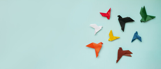 eight paper origami pigeons different colors on light blue background