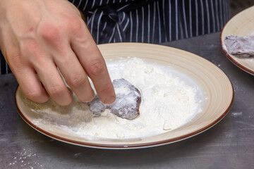 Cook sprinkles calf liver in wheat flour