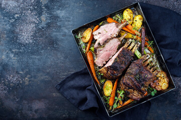 Traditional barbecue rack of lamb with carrot and potatoes served as top view on a rustic metal...