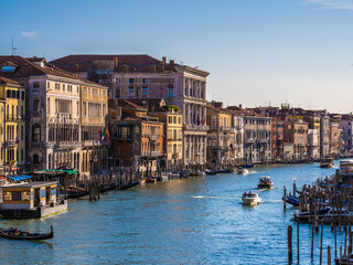 View of facades of picturesque old buildings on the Grand Canal, gondolas and boats in Venice. Sunny summer day with blue sky