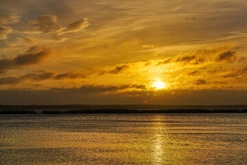 Fototapeta premium Sunrise over the lake. Sunlight breaks through the clouds.