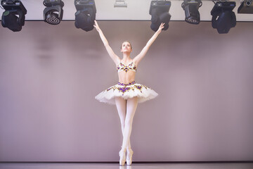 Graceful classic ballerina dancing, posing isolated on purple studio background.The grace, artist,...