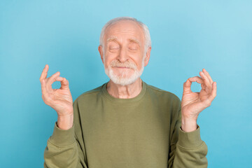 Portrait of attractive cheerful funny grey-haired man meditating free time isolated over bright blue color background