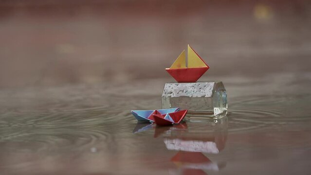 Origami paper boat in a puddle of rainwater.