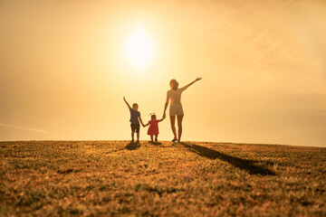 Fototapeta premium Happy mother and children in the park holding hands 