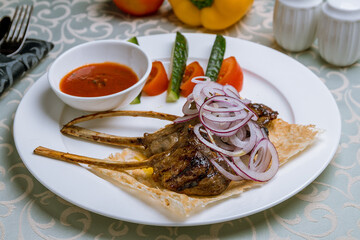 Rack of lamb with tomato sause on white plate