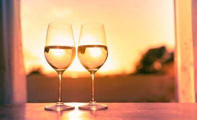 Pair of wine glasses on a bar at sunset 