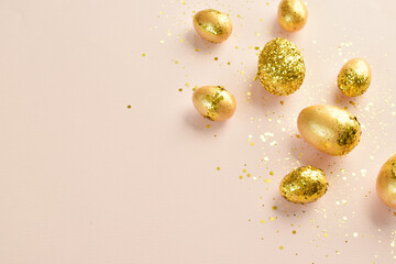 Easter eggs with gold sequins on a beige background. Banner for a happy Easter holiday. Space for copying. Flat position, top view