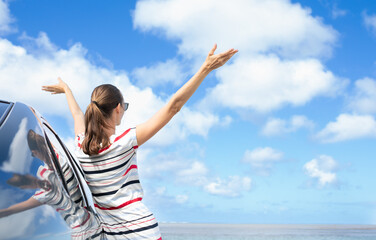 Happy woman traveler with arms up to the blue sky feeling positive in a happy state of mind