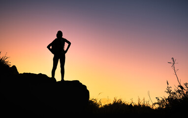 silhouette of woman standing on a hill top looking out at the view 