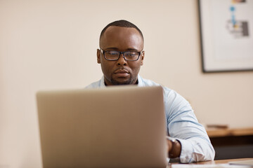 Focused on his immediate tasks. Cropped shot of a handsome young businessman working on his laptop at home.
