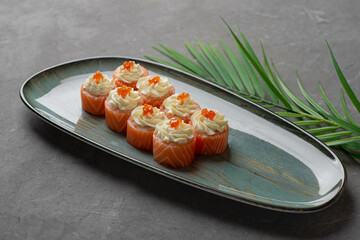 Philadelphia sushi with cream cheese on top and red caviar on a gray plate