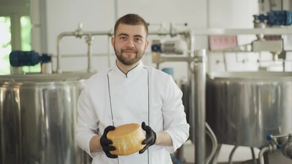 Portrait of a craft cheese worker. A cheesemaker inspects the cheese and looks at the camera. Craft cheese production technology