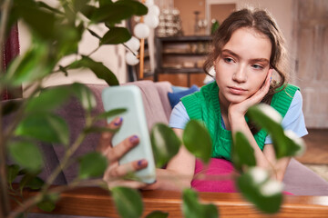 Woman holding her smartphone and posing to the camera while making selfie at home