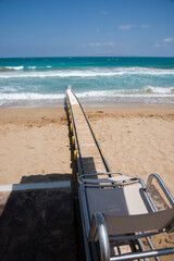 Safe motorized wheelchair ramp with build in fresh water shower, used to transport disabled people into the sea water for swimming. Heraklion, Crete, Greece