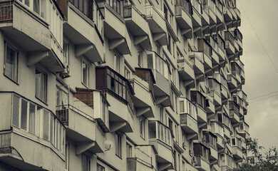 Windows and balconies of the residential building. Old urban obsolete facade of house. The windows...