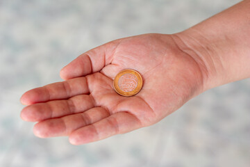 One real coin in the palm of a person's hand. Hand holding a 1 dollar coin. Real is the currency system of the Brazilian Government