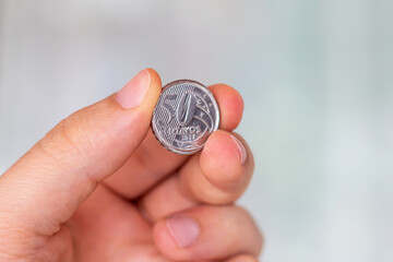 Brazilian 50 cents coin in the palm of a person. Hand holding a 50 real cents coin. Real is the...