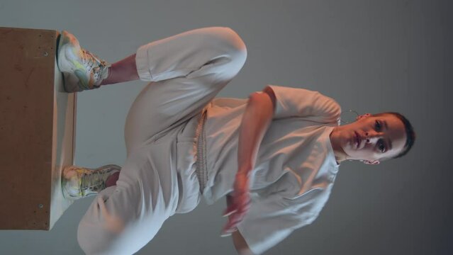 Dancing blogger girl with short hair perform modern dance in studio, record vertical video for social media. Prores