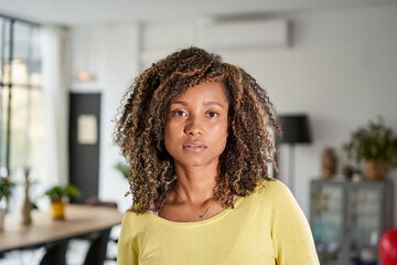Portrait of a beautiful young adult woman serious expression face. African girl in casual looking at camera with. Confident mixed race relaxing at home.