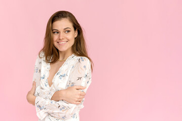 Obraz premium Smiling young enjoying caucasian woman in a summer dress on a pink background. Charming lady in white outfit posing with a happy expression.
