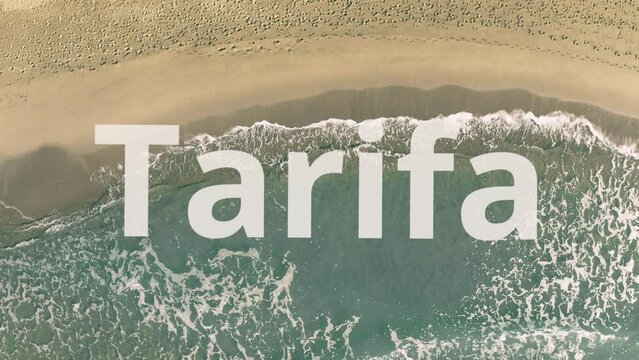 Tarifa word being revealed with the shadow of a flying airplane on the beach