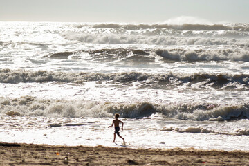Fototapeta na wymiar Boy Running in Huge Waves During Cyclone