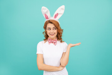 Obraz na płótnie Canvas happy easter woman with bunny ears on blue background. presenting product