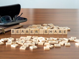 bearer share word or concept represented by wooden letter tiles on a wooden table with glasses and a book - obrazy, fototapety, plakaty