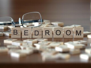 bedroom word or concept represented by wooden letter tiles on a wooden table with glasses and a book