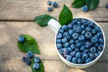 A bowl with fresh bilberry (Vaccinium myrtillus) on an old wooden bench. Fresh garden blueberries.