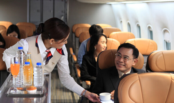 Cabin Crew Pushing Service Cart And Serve To Customer On The Airplane During Flight. Hostess Service On Plane