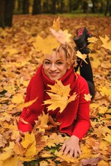Naklejka na ściany i meble Beautiful female autumn session. Girl with blonde hair in a city park among autumn leaves.