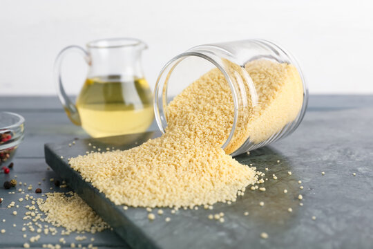 Jar with raw couscous on table