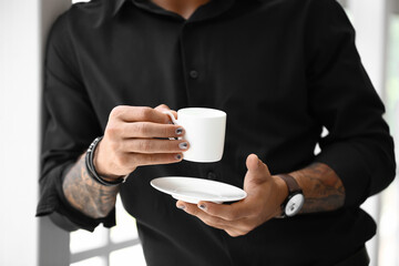 Fashionable man with trendy manicure holding cup of coffee