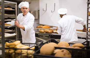 Man transporting cart with bread in the bakery