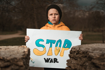 A boy who lives in Ukraine holds a white poster with the inscription Stop War