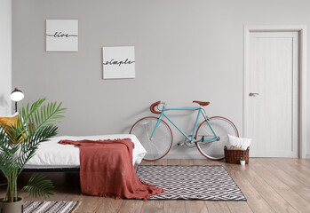 Interior of stylish bedroom with comfortable bed and bicycle