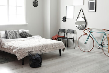 Interior of light bedroom with modern bicycle and chairs