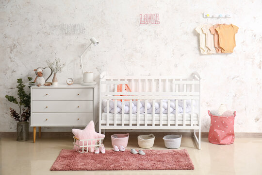 Interior of light children's bedroom with crib and baby bodysuits
