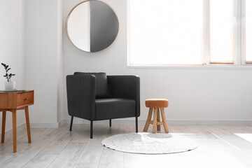 Black armchair, stool and table in light living room