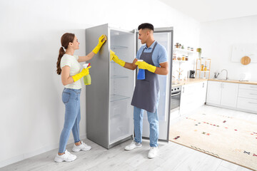 Young couple cleaning refrigerator in kitchen